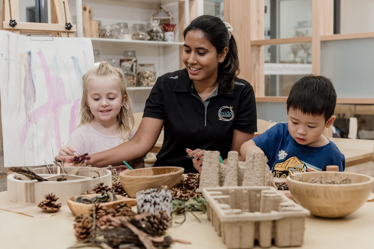 Nido educators help children in playing with natural materials for hands-on sensory experiences