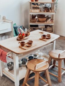 Wooden tray, bowls and spoons placed at wooden dining table