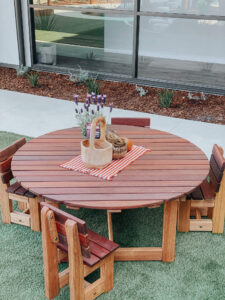 Wooden table and chairs with flower basket placed at grass floor at garden area