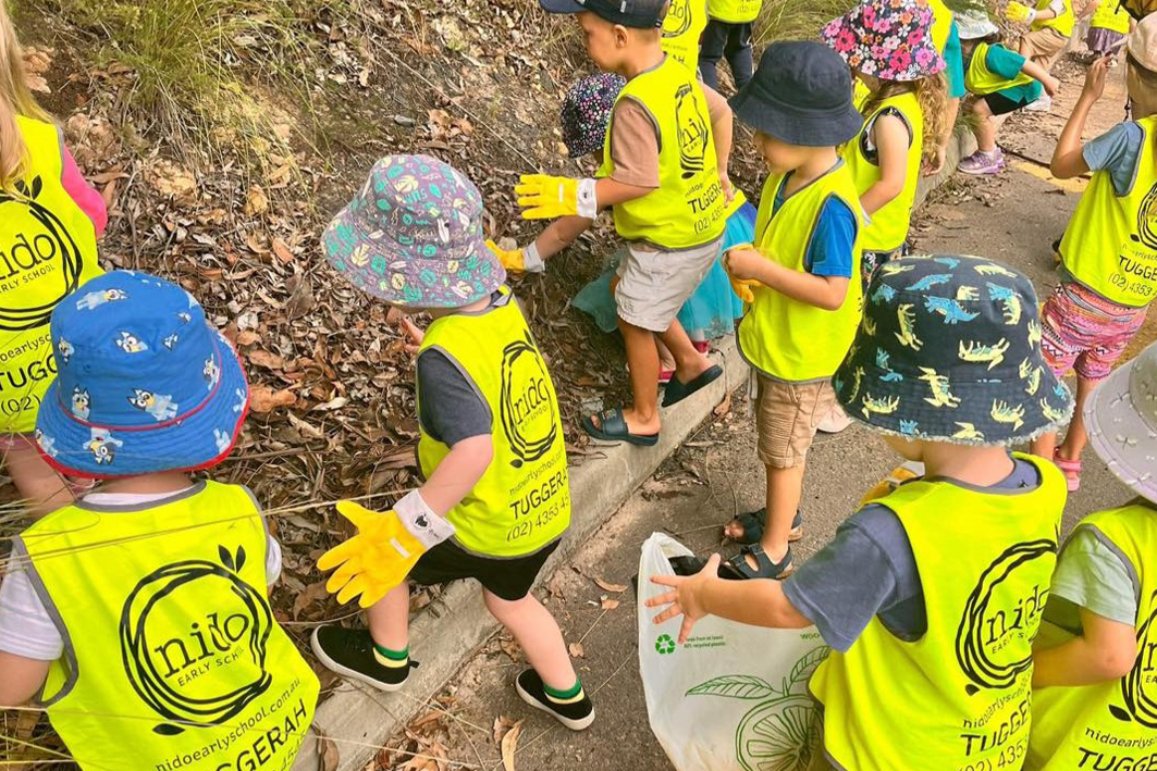 Children in yellow vests and hats join clean up Australia day activities at Nido.